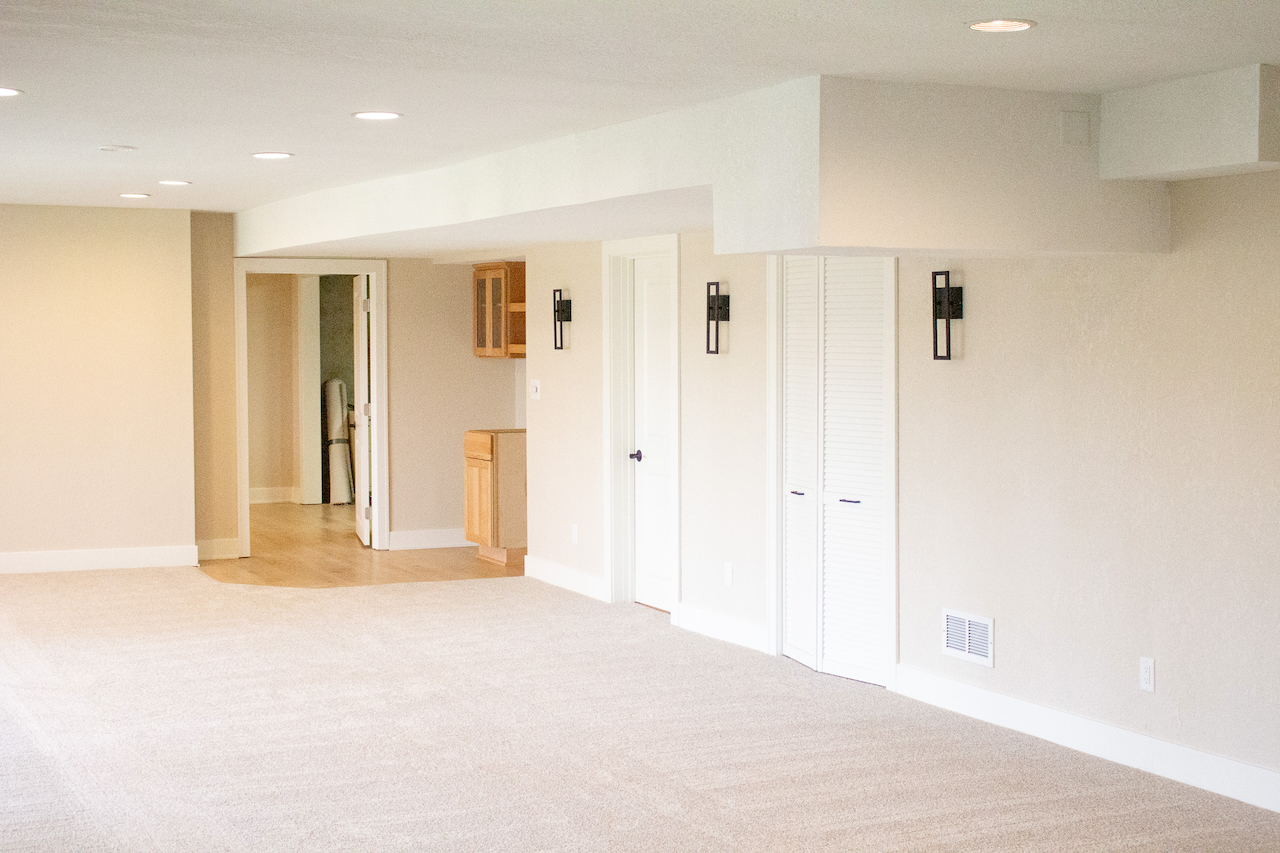 Finished basement living area with carpet, closet doors, and wall sconce lighting