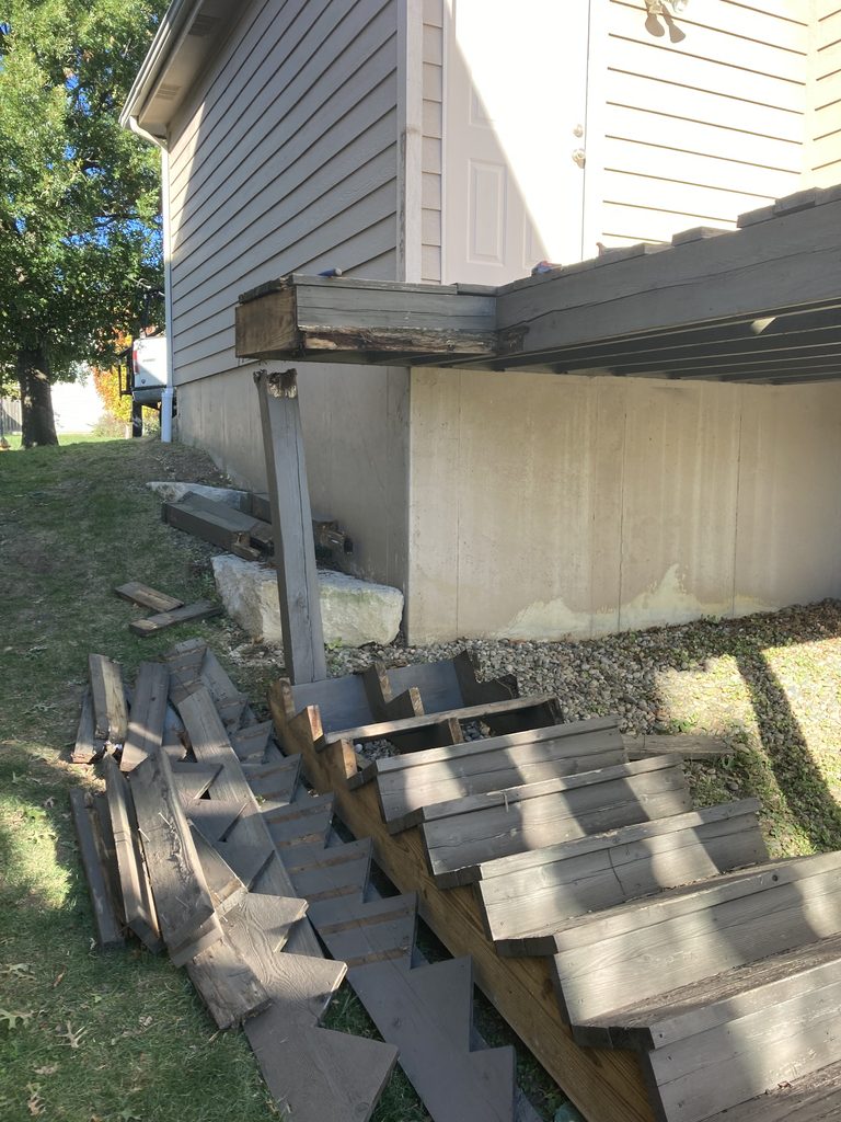 Collapsed deck stair stringers resting on a sunken support post