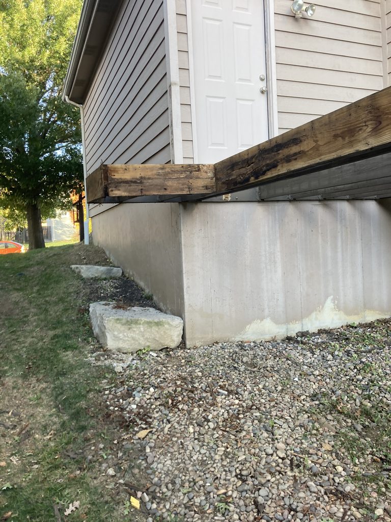 Deck support post and overhang beam before repair, stone footing visible