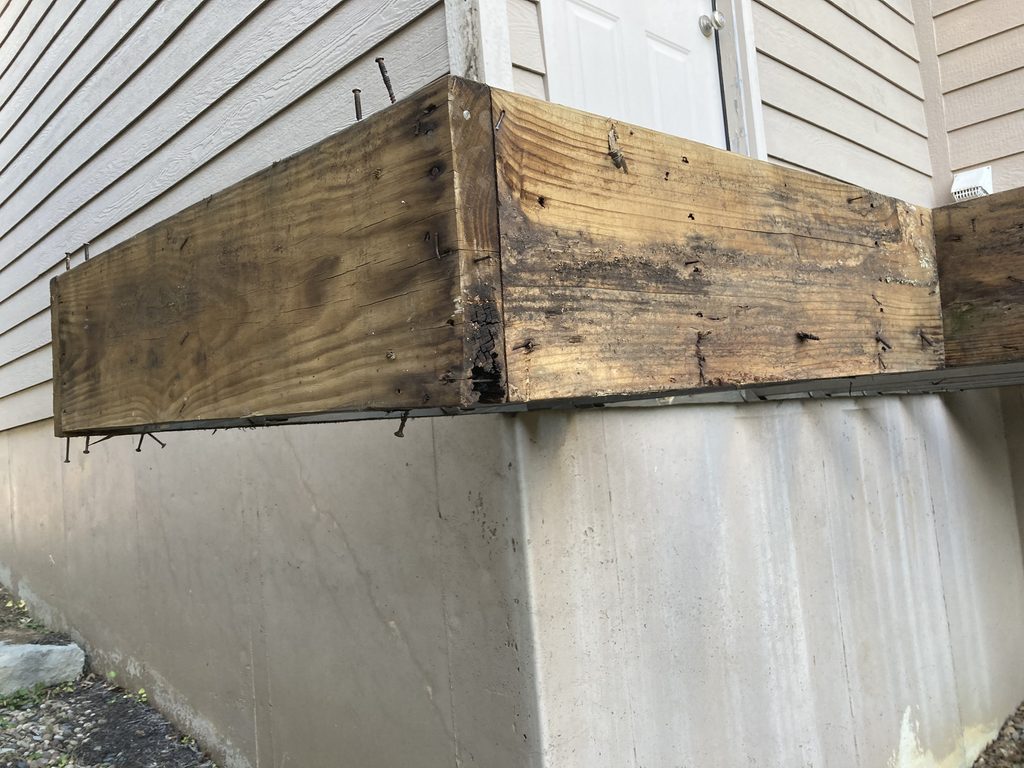 Close-up of a cracked and weathered beam corner with exposed nails