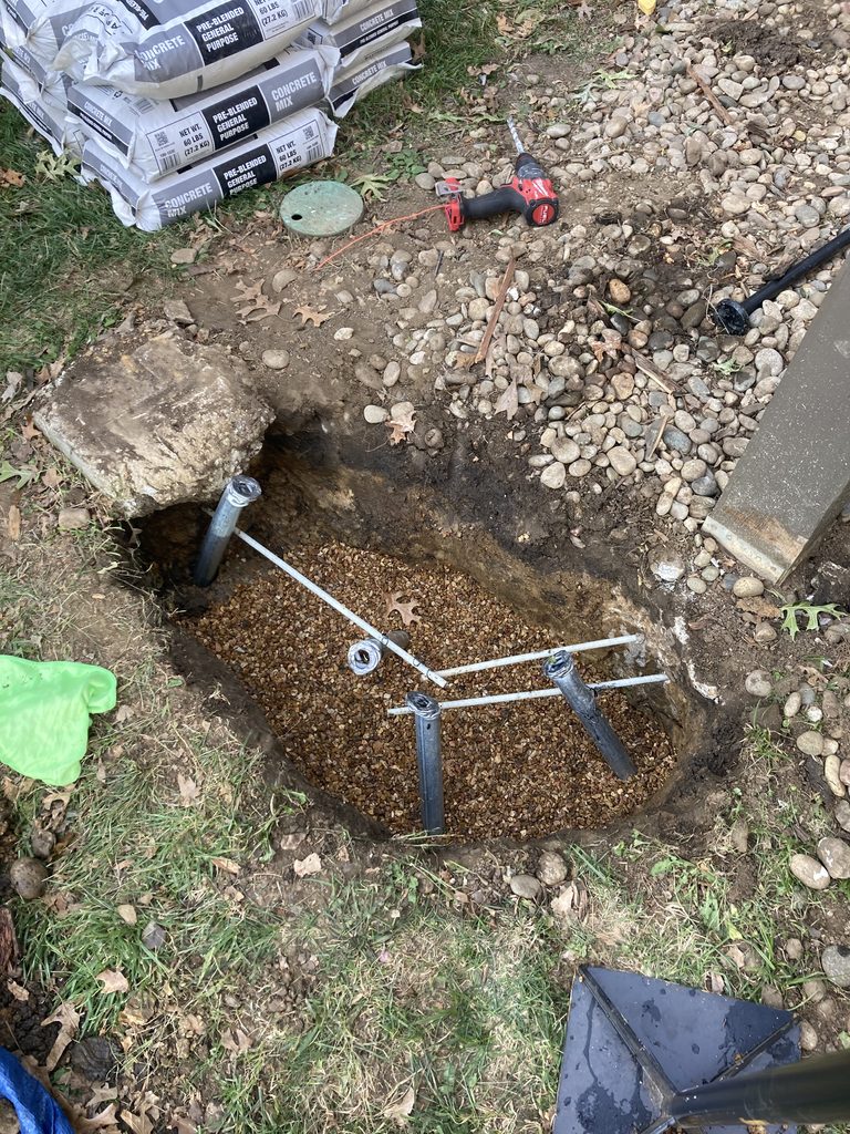 Excavated pier hole with concrete bags staged for the pour