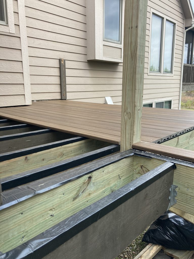 New composite decking corner installed beside the entry door