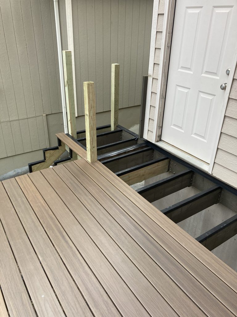 New composite decking and support posts installed near the entry door