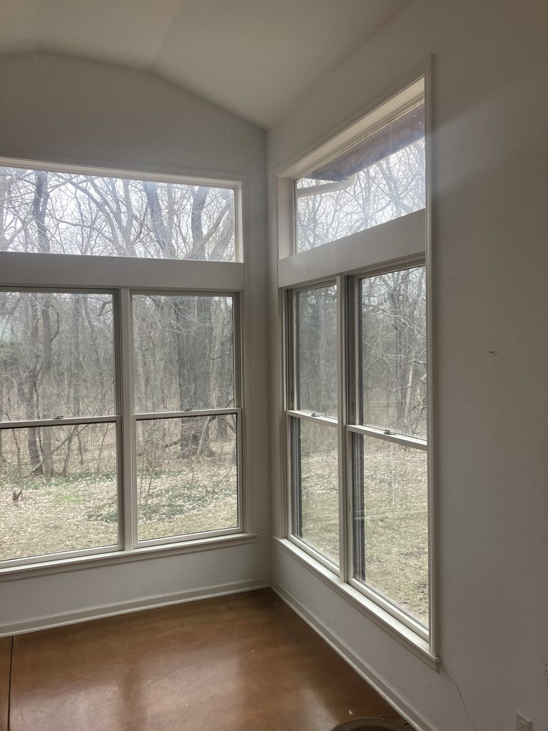 Bright sunroom corner with tall windows before the drywall and paint work began.