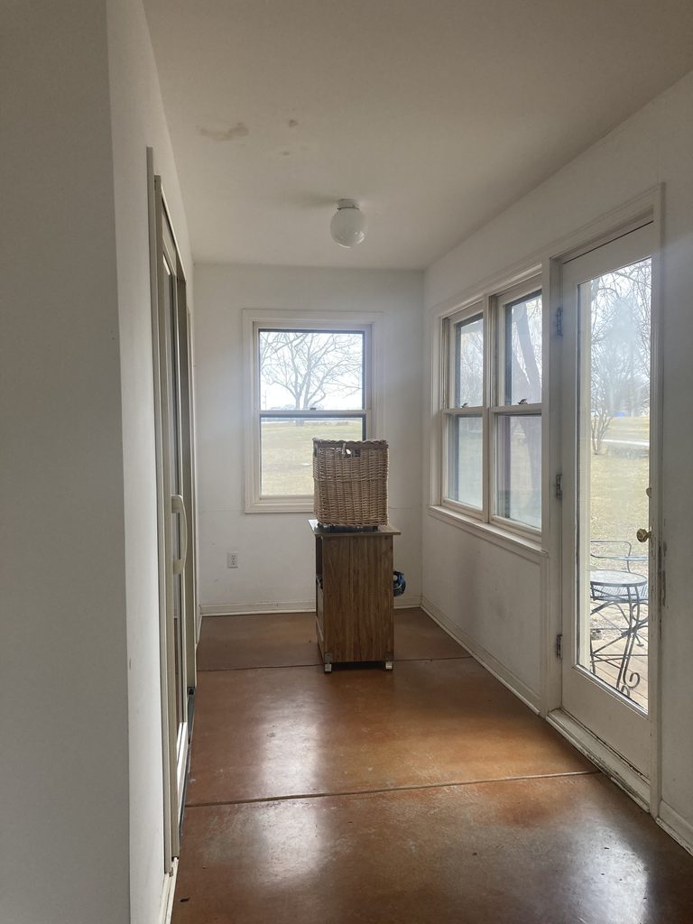 Sunroom hallway with concrete floor and door leading outside before the renewal.