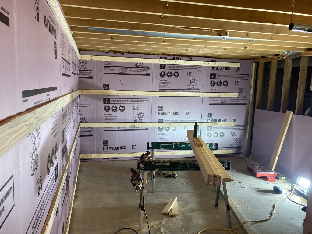 One-by-four wall framing set against the insulated basement wall