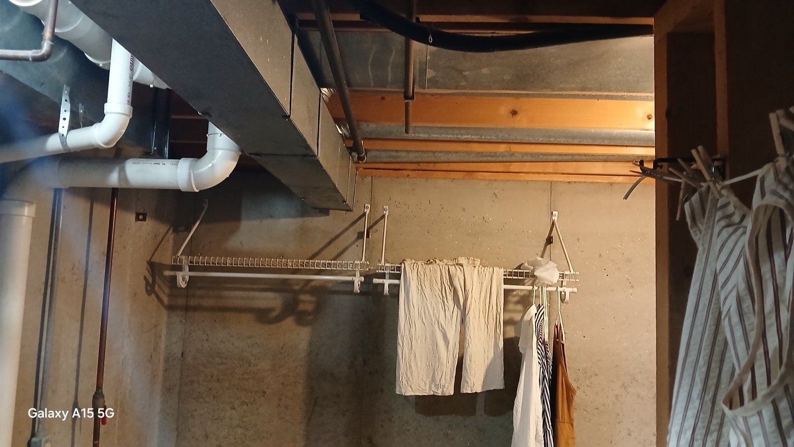 Bare concrete walls and exposed ductwork in the laundry area before basement finishing began.