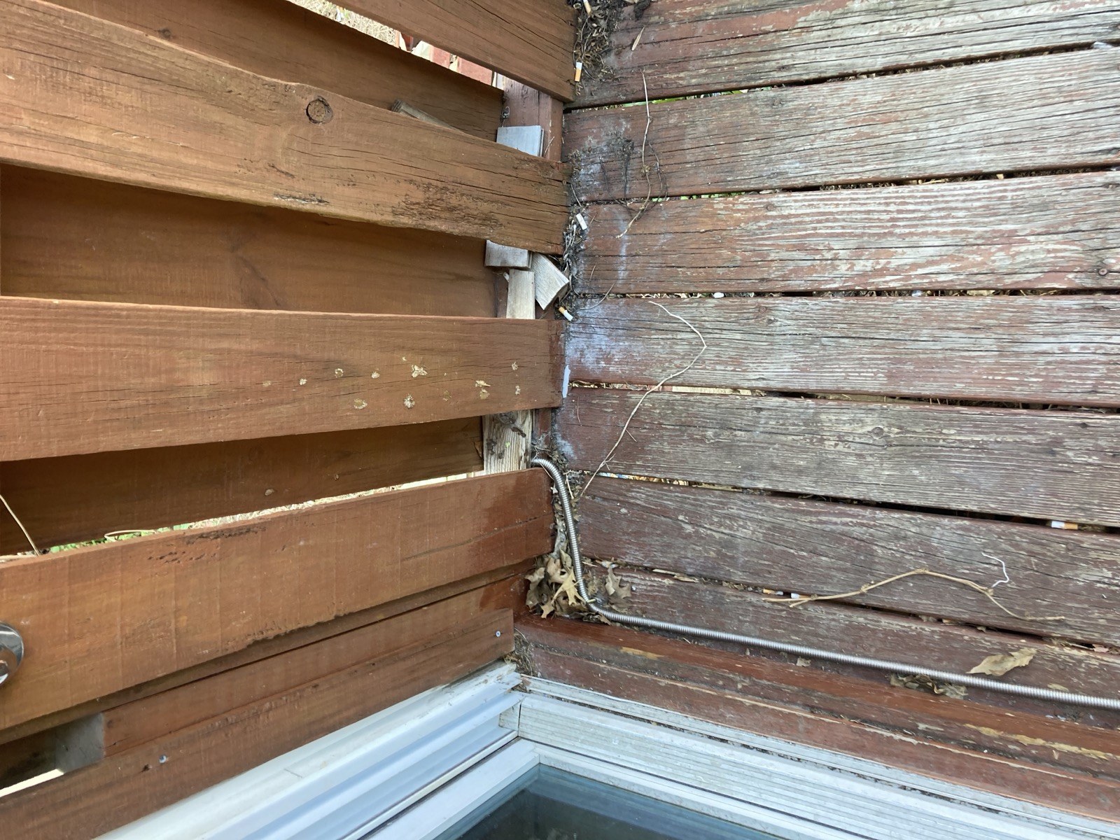 Close-up of the deck boards and rim board where they meet the sliding door threshold, showing worn and stained wood