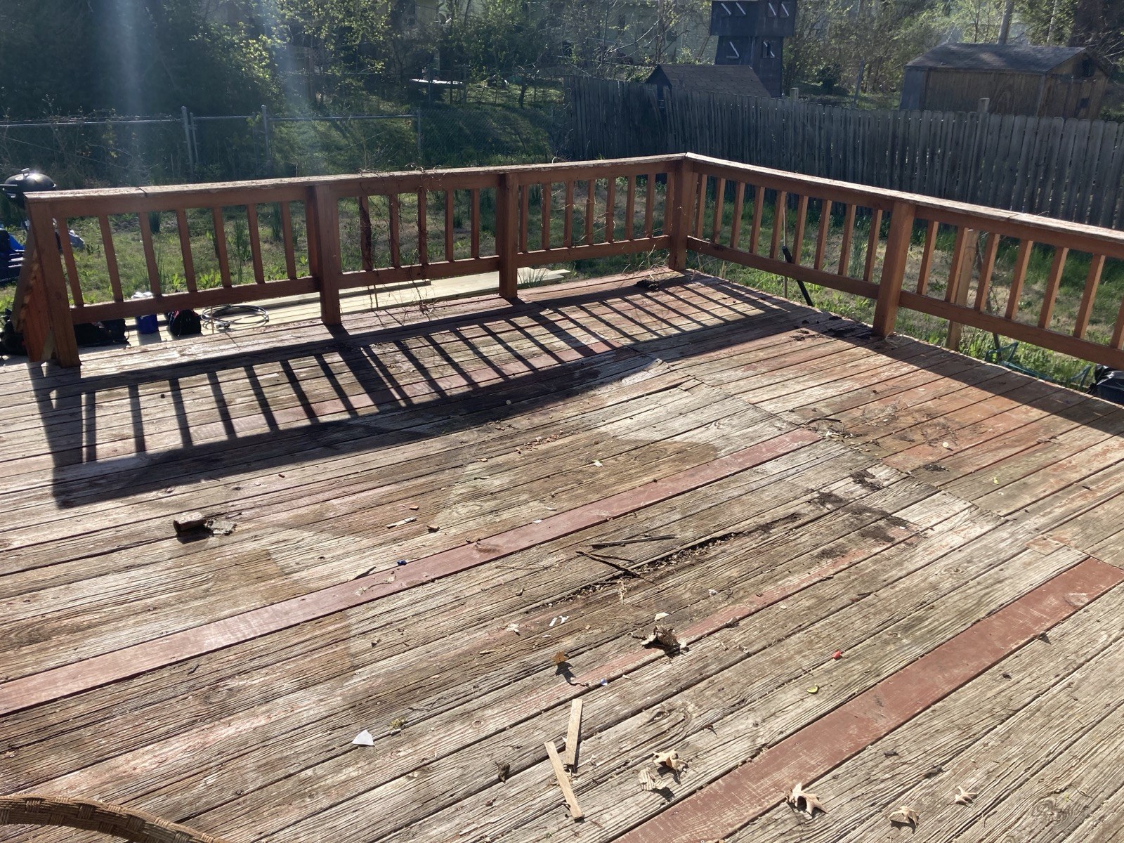 Opposite corner of the existing deck showing the full railing perimeter and worn decking surface