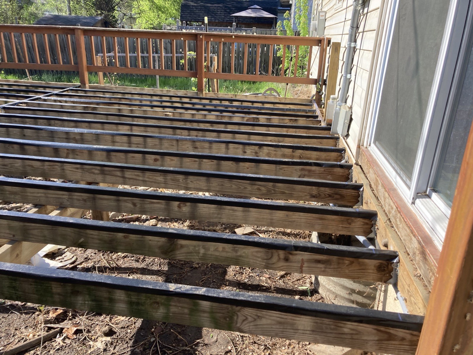 Old decking removed, exposing the joists and rim board along the house wall