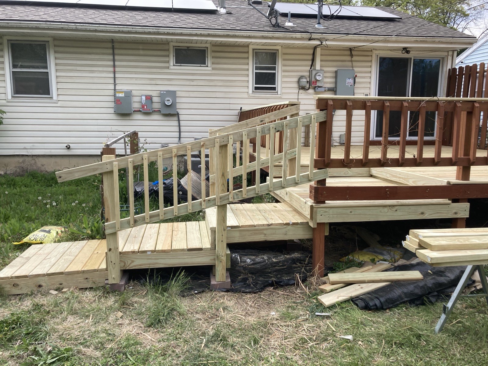 Finished deck with new railings, decking, and an access ramp with steps leading down to the yard