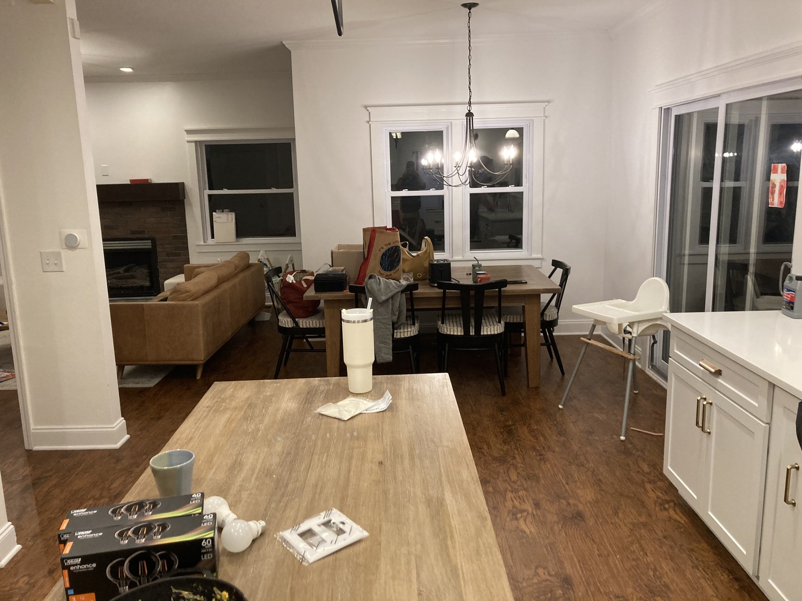 Open dining and living area with wood dining table, high chair, and sofa on wood flooring