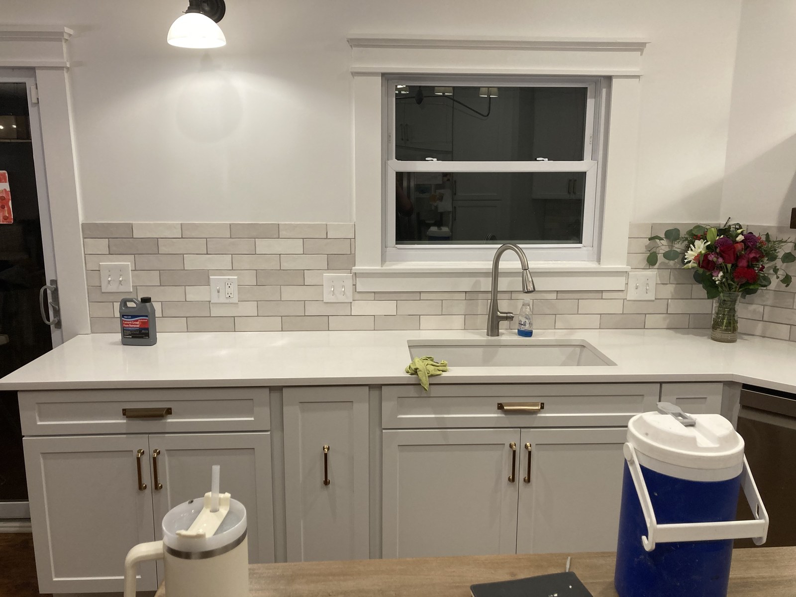 Stainless faucet and undermount sink below a window framed by subway tile backsplash
