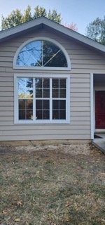 Front elevation showing completed siding repair with arched window above entry