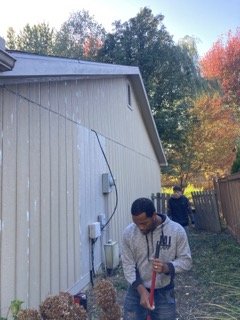 New siding installed on gable end wall with worker in foreground