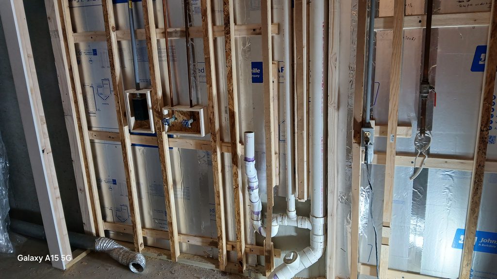 Framed wall with washer supply valve box and drain pipe roughed in.