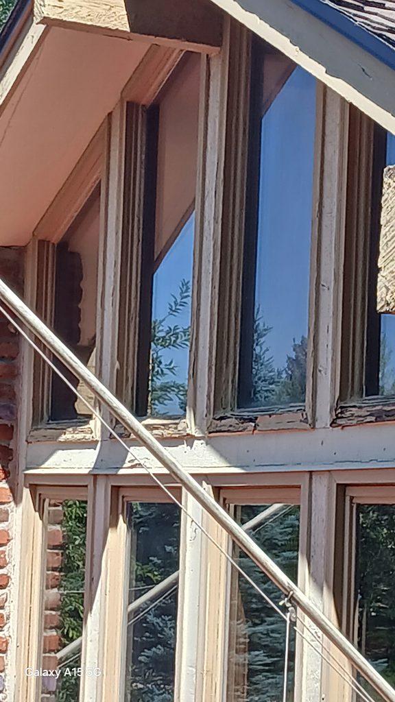 Deteriorated, rotted wood trim around the upper windows before replacement.
