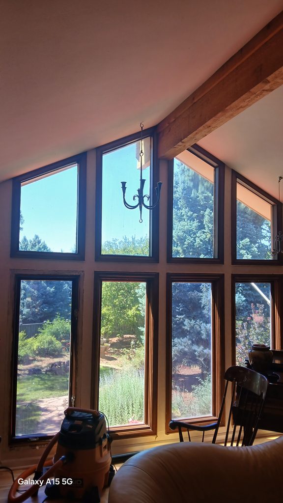 Tall vaulted living room window wall with old wood-framed windows before replacement.