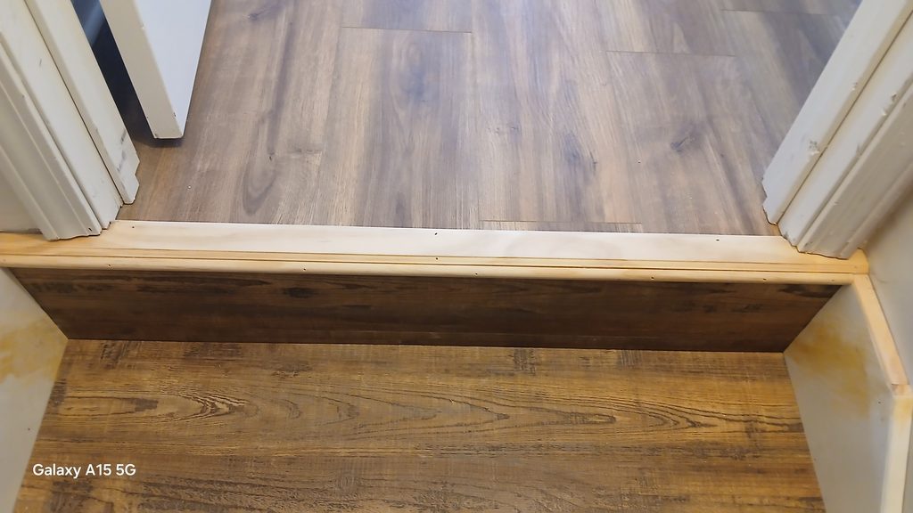 Vinyl plank stair tread and riser at the top of the finished basement stairs.