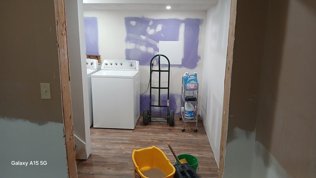 Finished laundry room with vinyl plank floor and washer and dryer in place.