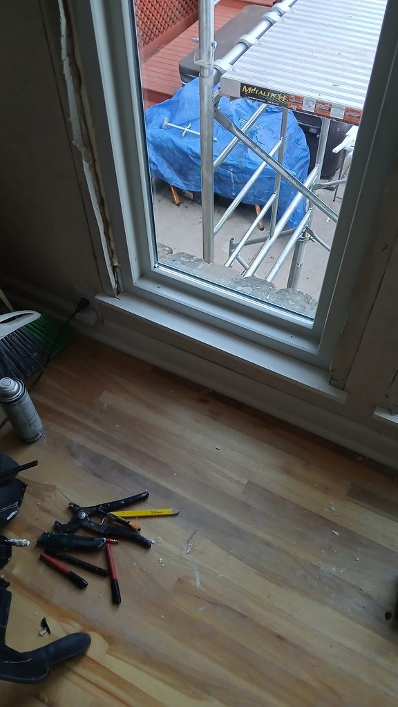 Close view of a new window installed with exposed framing around the jamb, tools on the floor.