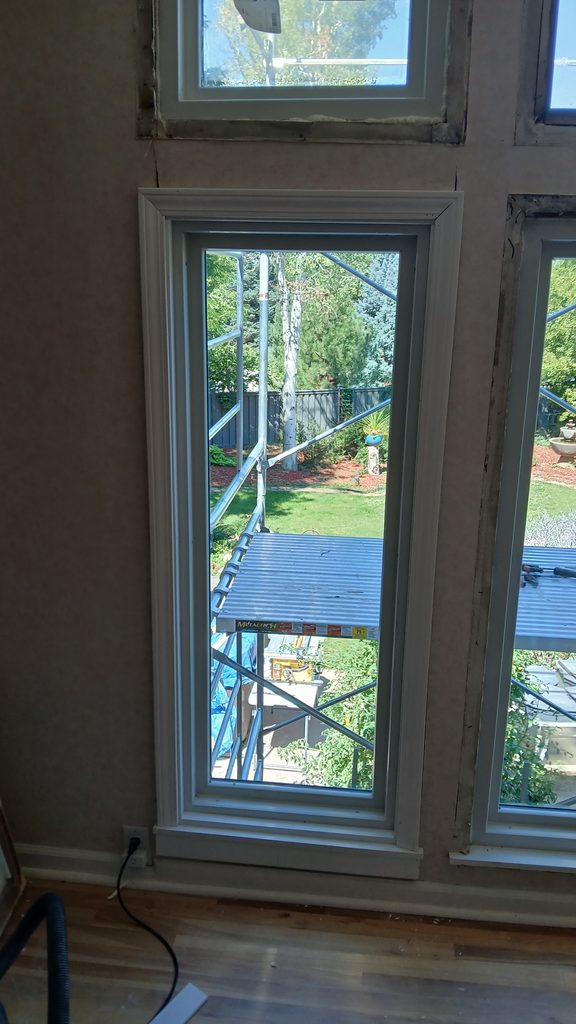 Comparison of a finished white window casing next to an untrimmed window opening.