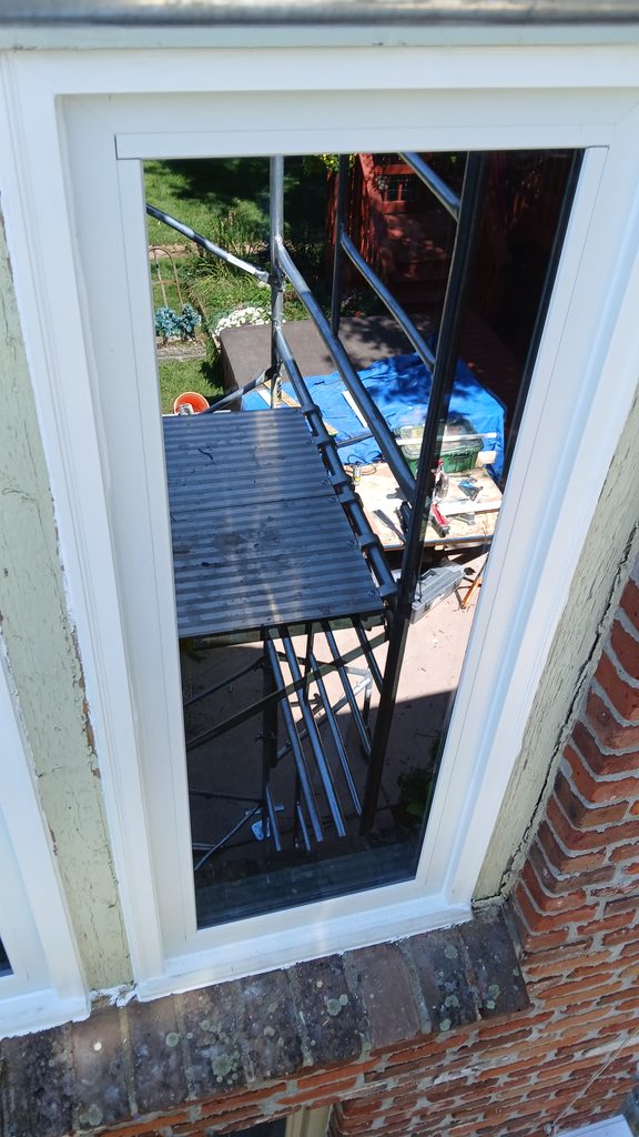 Exterior close-up of a new window and white trim, seen from the scaffold platform.
