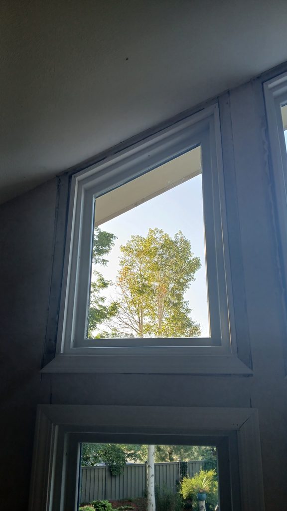 Primed white trapezoid window casing set into the angled ceiling line.