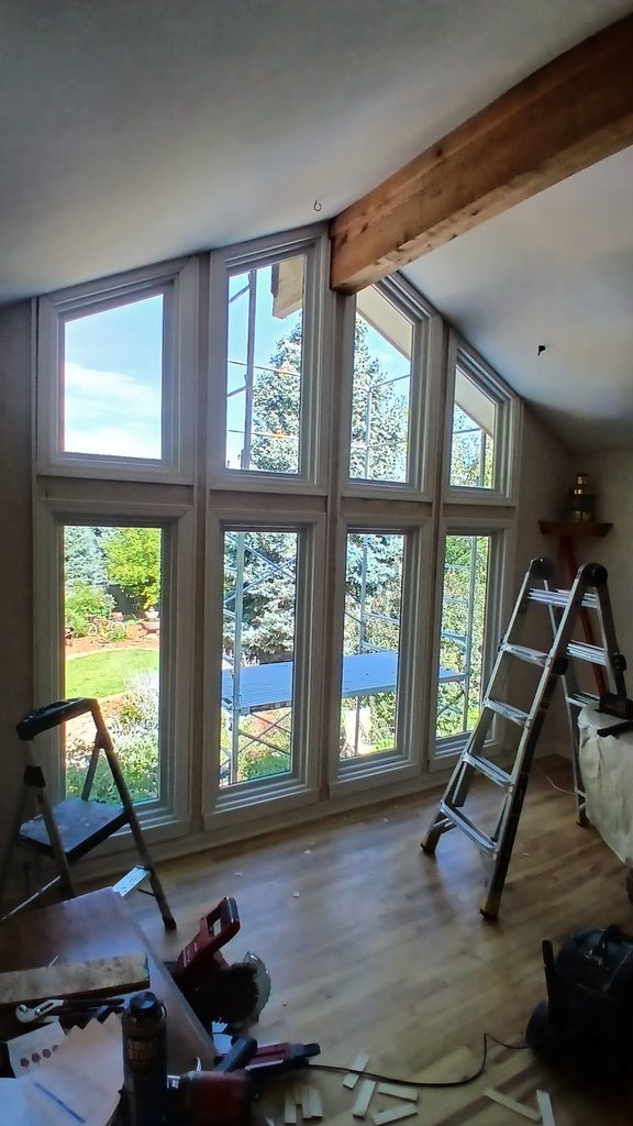 Interior view of the completed two-story window wall with primed casing, tools staged nearby.