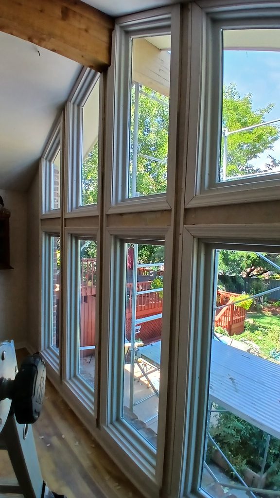 Close angled view of mitered window casing joints along the full window wall.