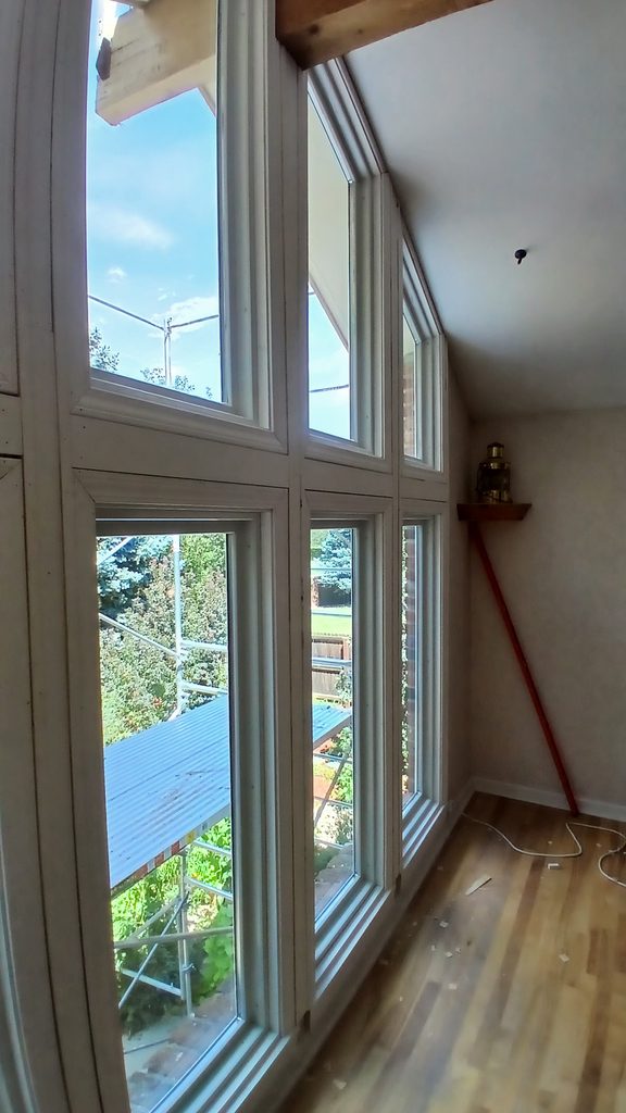 Interior corner view of the completed window wall with custom angled casing tying into the beam.