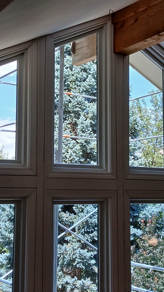 Close view of mitered white window casing corners at the roof peak beam.