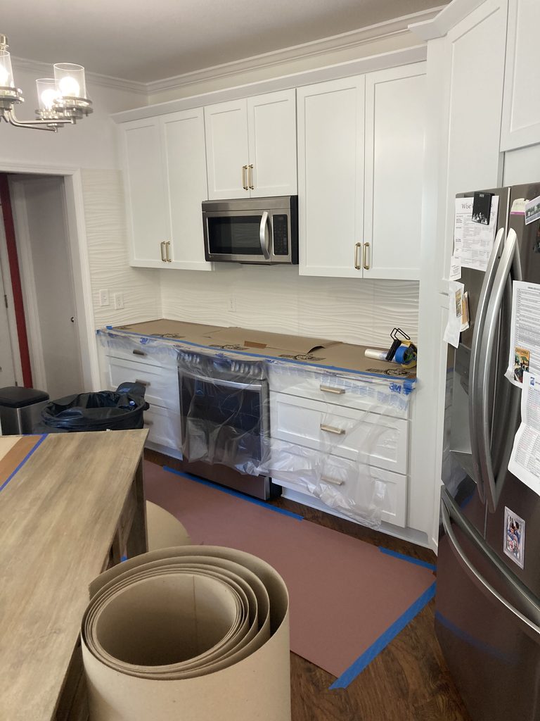 Kitchen cabinets and refrigerator covered in plastic and paper before the remodel