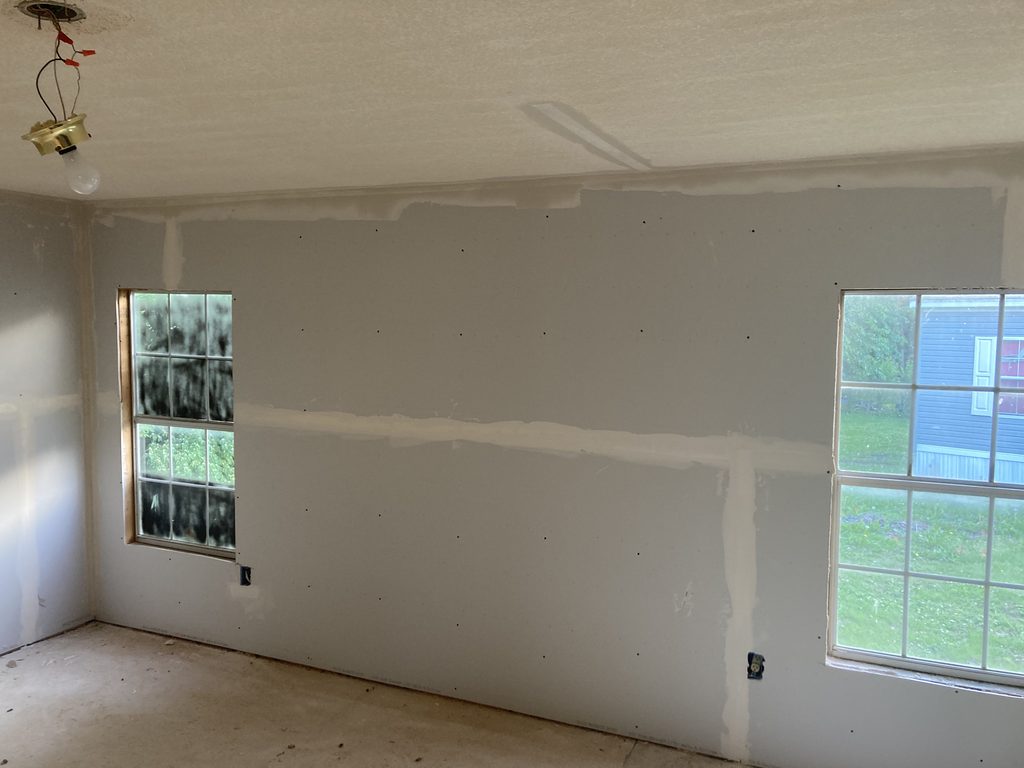 Finished drywall seams taped and mudded in a bedroom with two windows.