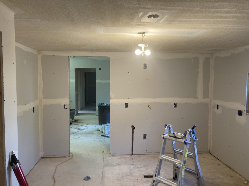 Finished drywall in a bedroom with a stepladder set up near the doorway.