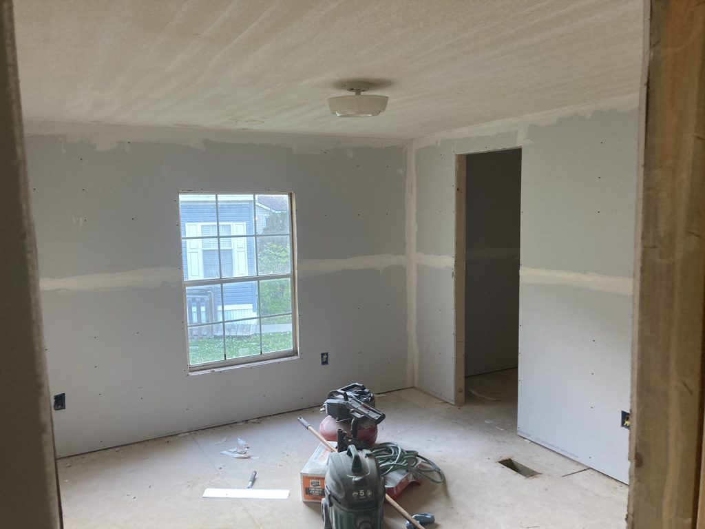 Finished drywall room with a stepladder set up in the corner.