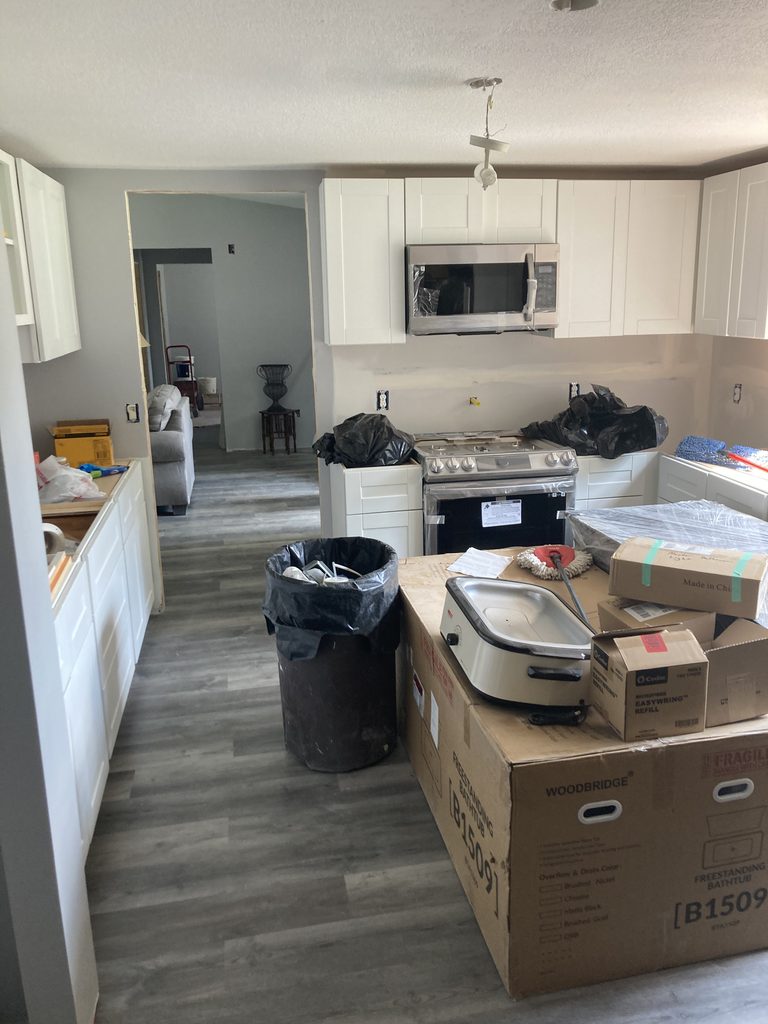 White kitchen cabinets with a stainless microwave and range over finished vinyl plank flooring.