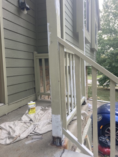 Porch corner post being prepped and painted with a drop cloth on the deck.