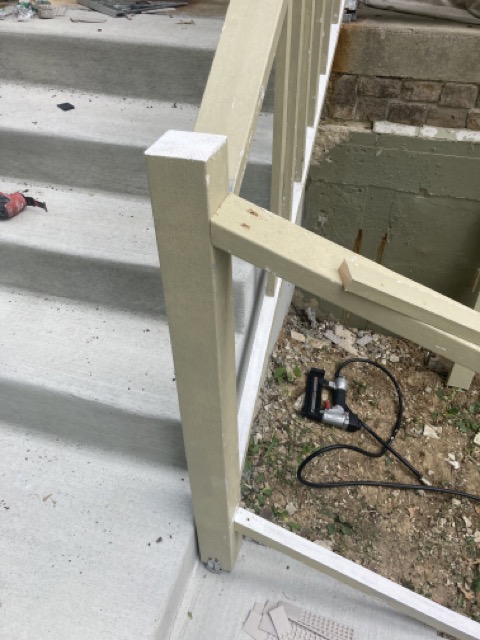 New wood railing post with a diagonal brace at the bottom of the concrete steps.