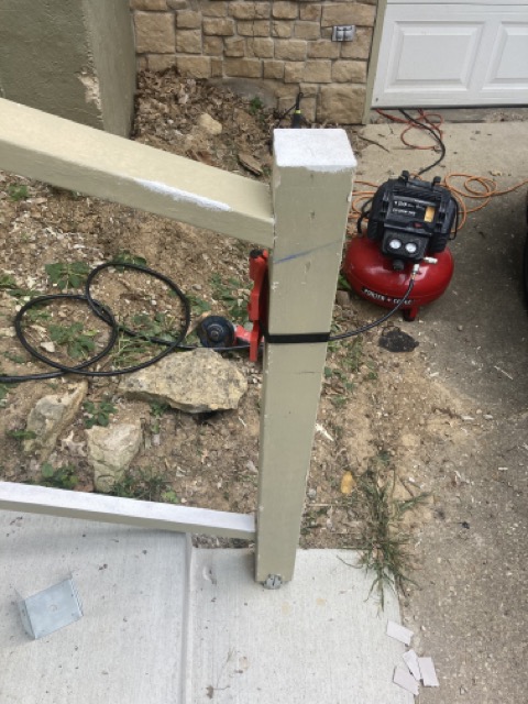 Close-up of a railing post base fastened to concrete steps with a metal bracket.