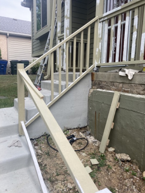 New railing post and diagonal brace being installed beside the driveway.
