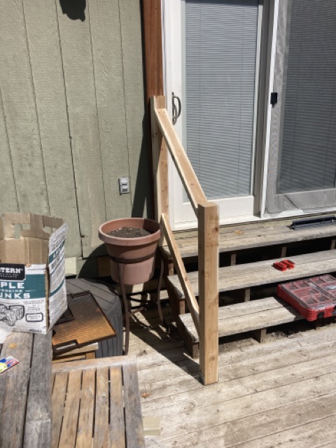 Unpainted wood railing framing being built on the back deck near the sliding door.