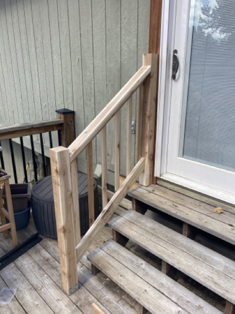 Completed wood railing with spindles on the back deck steps, unpainted.