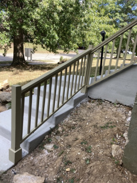 Finished sage-green railing along a long run of concrete steps toward the street.