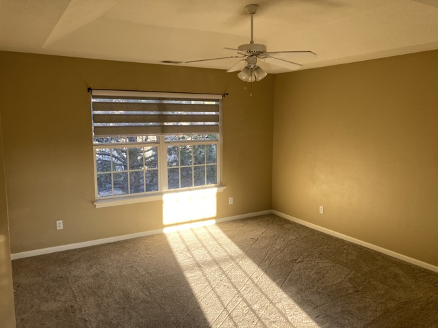 Empty master bedroom with tan walls and carpet before the renovation.