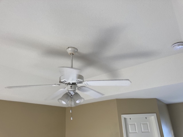 Bedroom ceiling fan and corner of tan wall before the renovation.