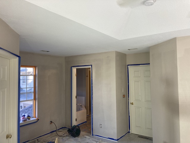 Hallway and closet walls freshly painted gray with doors taped for protection.
