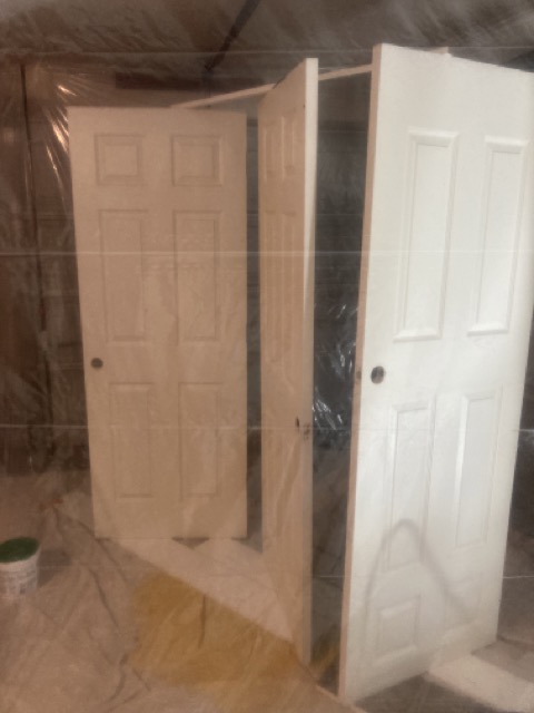 Two white six-panel doors drying after being spray painted.