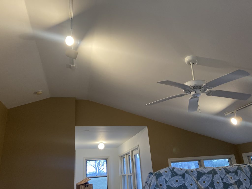 Finished vaulted ceiling with a ceiling fan and track lighting after the paint work.