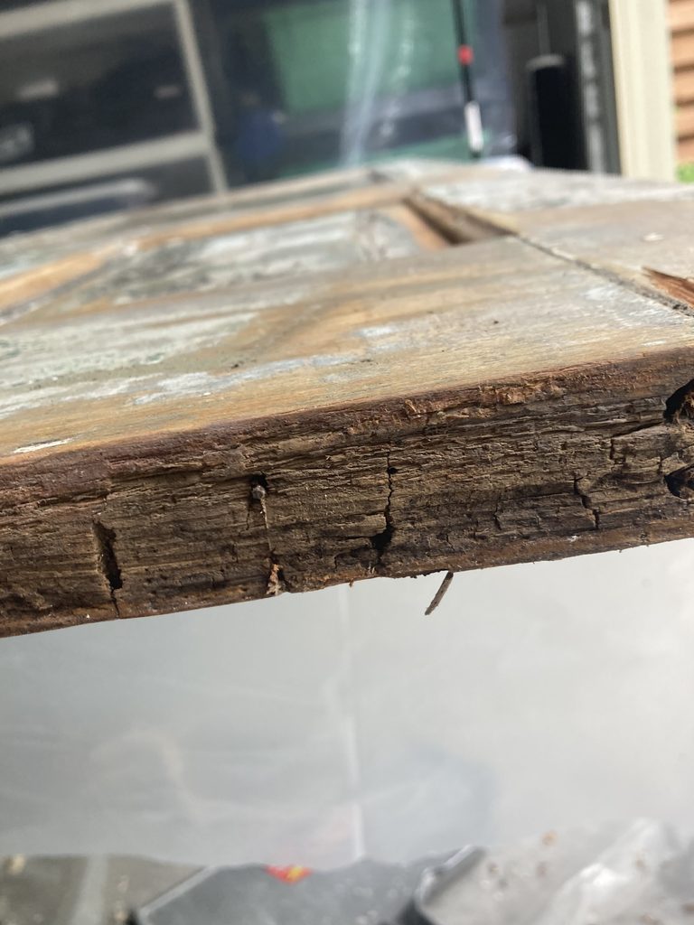 Close-up of rotted, splintering wood at the corner of a door component.